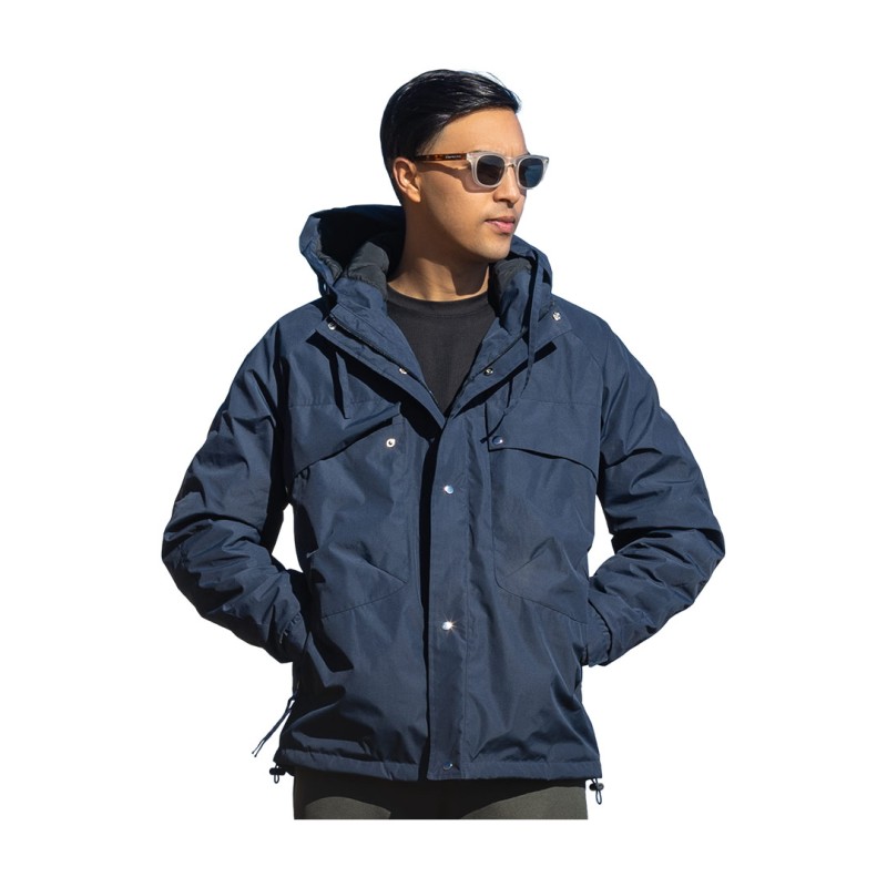 A male model wearing sunglasses and a heavy-duty, navy blue KTM CTY Cargo Shield Hoodie Winter Jacket, featuring a thick hood, snap-button front and multiple cargo pockets for cold weather protection.