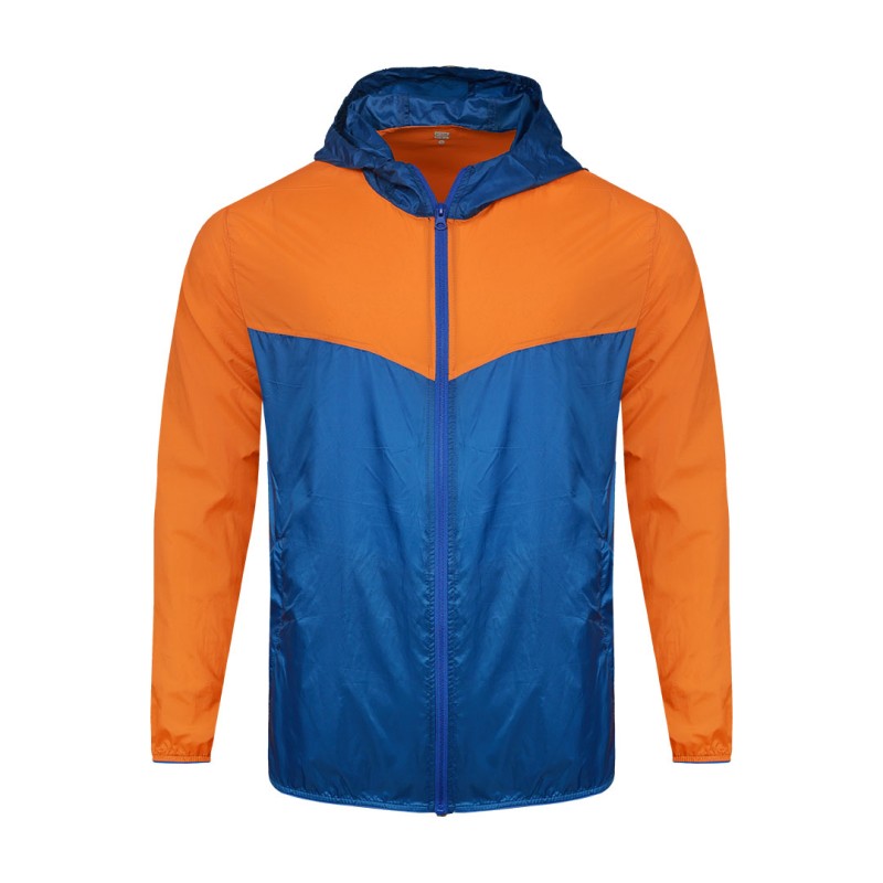 Front view of a male model styling a vibrant red and blue color-block lightweight windcheater jacket. This casual Unisex Windbreaker Jacket features a full zipper and a protective hood, making it a great outer layer for summer wear jacket. 0