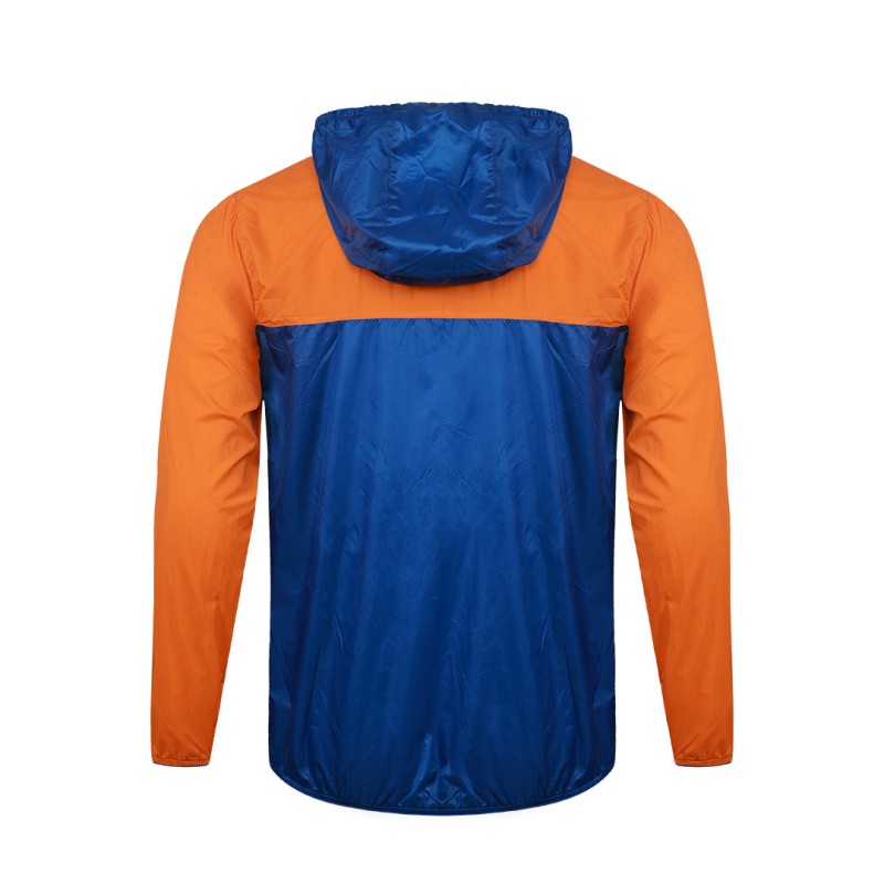 A smiling male model wearing the lightweight SkyShield Windcheater Jacket, featuring a bold red and bright blue color-block design, a full front zipper and an adjustable hood 1